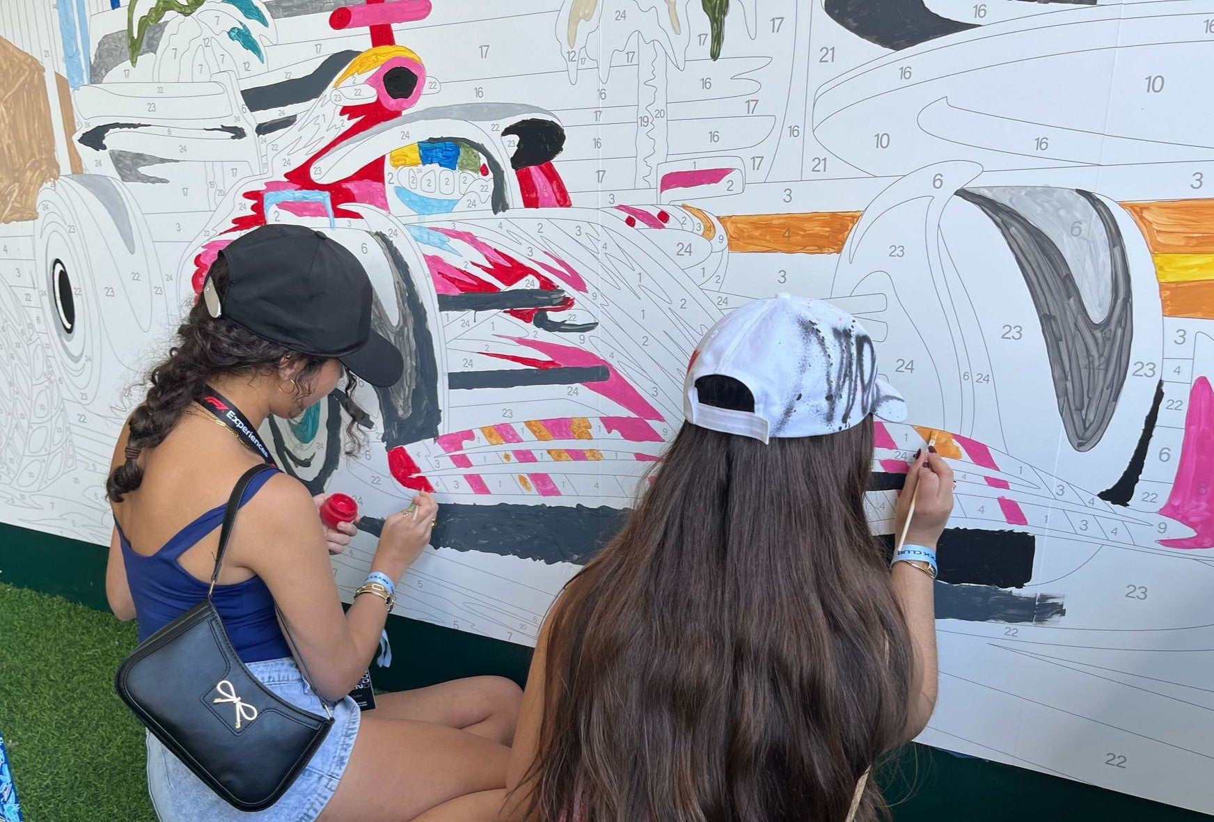 two women painting a paint by number mural at a large professional racing event in Miami, FL