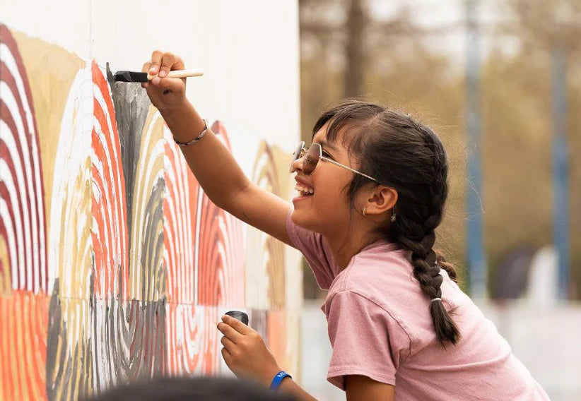 girl at a largest NASA festival painting a paint by number mural, smile