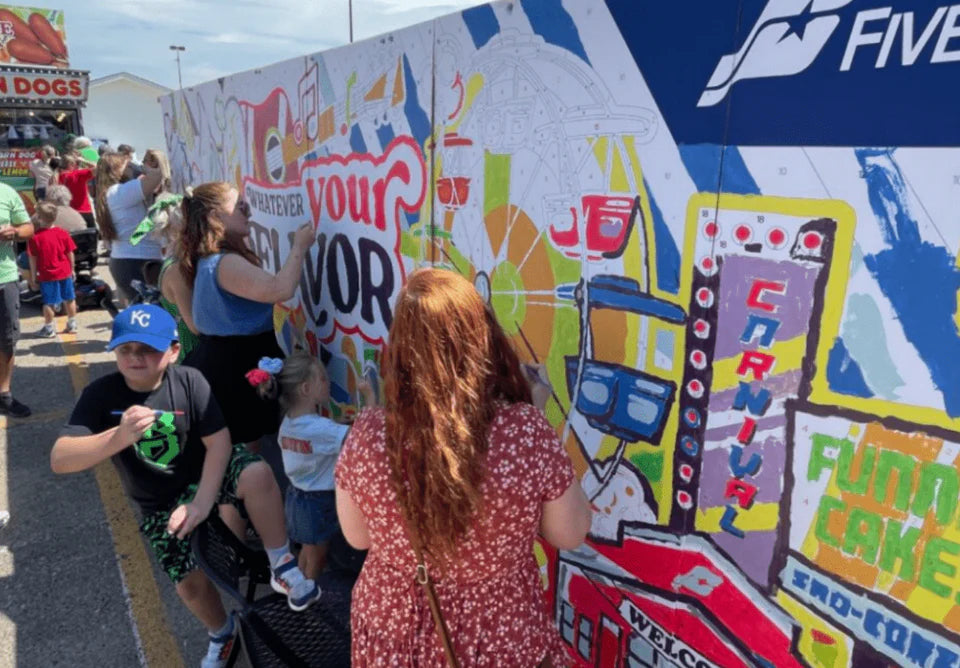 A large crowd painting  a paint by number mural at the Nebraska State Fair. The paint by number mural is sponsored by Five Points Bank.